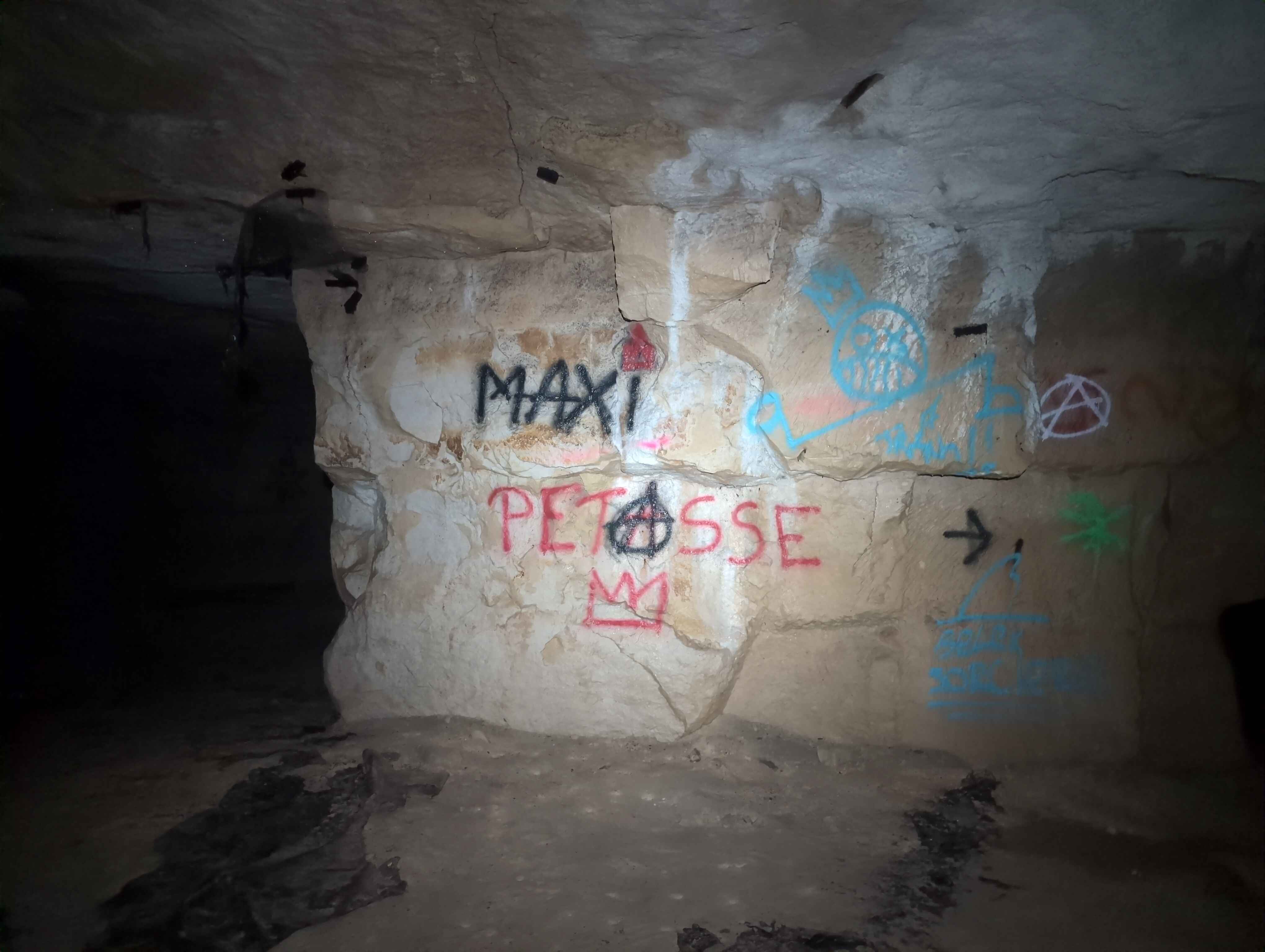 Tag sur un muir de la carrière disant 'Maxi Pétasse' 
